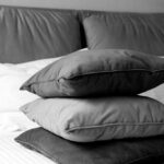 Felipe Peña contemporary art: A black and white photo shows three neatly stacked pillows on a quilted bed. The pillows vary slightly in texture and shade. In the background, a padded headboard and part of a white bedsheet are visible, creating a tidy, cozy atmosphere. , exclusive contemporary art for New York collectors